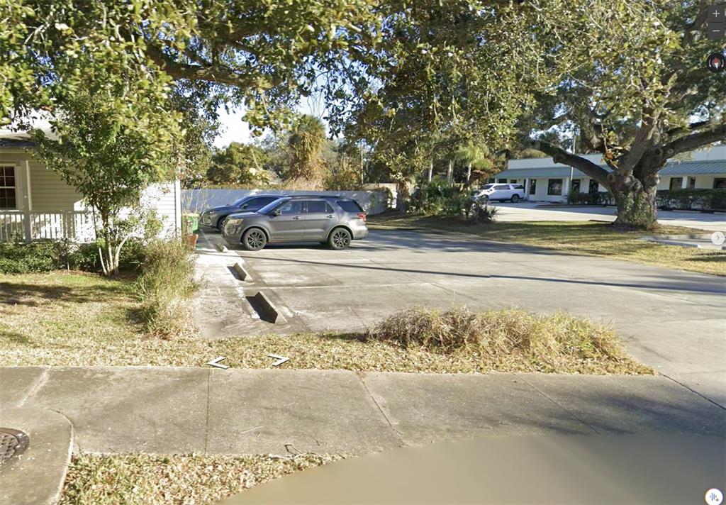 A paved parking lot sits next to a house under large, mature oak trees — 360 TANGERINE AVENUE, MERRITT ISLAND, FL