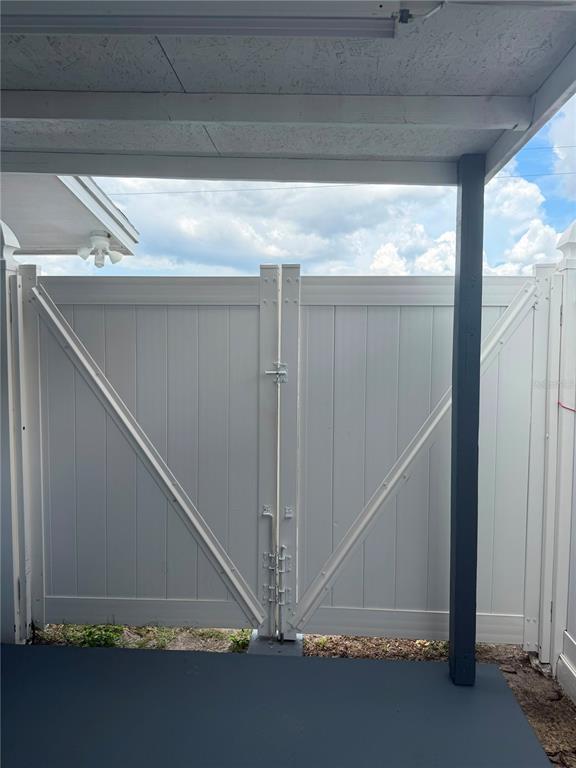 A white double gate with diagonal bracing stands at the edge of a covered patio — 4514 W FERN STREET, TAMPA, FL