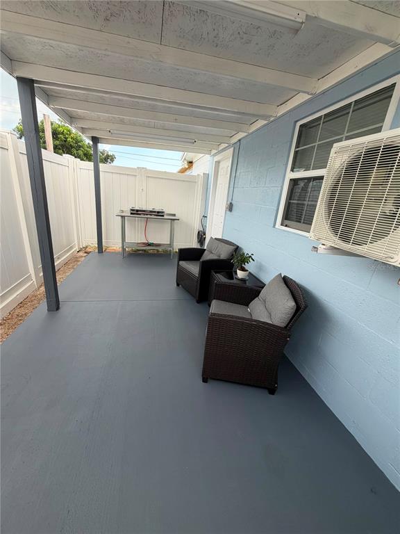 A covered patio with a painted concrete floor, two wicker chairs, and a metal table — 4514 W FERN STREET, TAMPA, FL