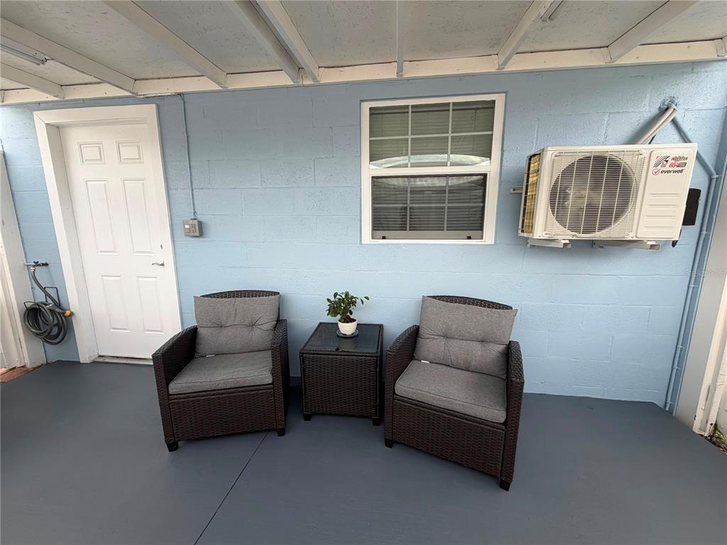 A covered patio features a light blue cinder block wall, two wicker chairs, and an AC unit — 4514 W FERN STREET, TAMPA, FL