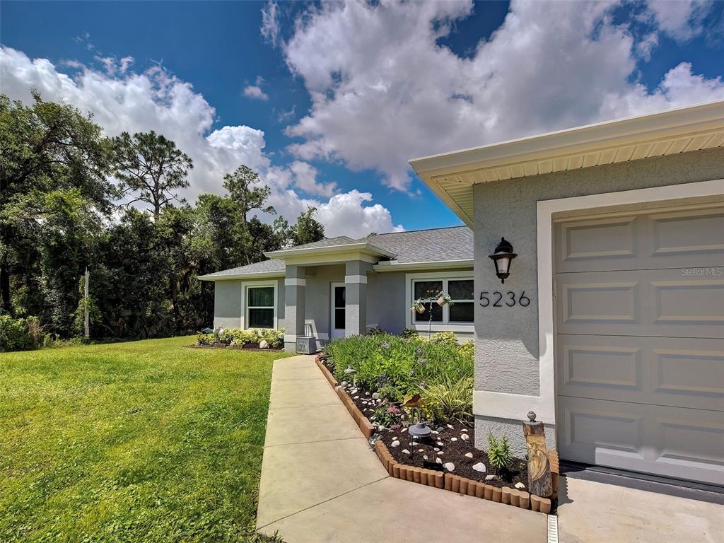 A single-story house exterior features a gray stucco facade, a garage, and a walkway — 5236 BANNOCK CIRCLE, NORTH PORT, FL