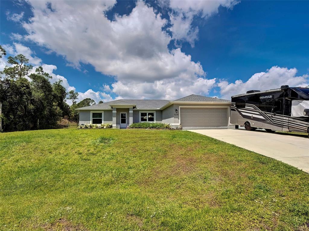 A single-story house with a gray exterior, a two-car garage, and a parked recreational vehicle — 5236 BANNOCK CIRCLE, NORTH PORT, FL