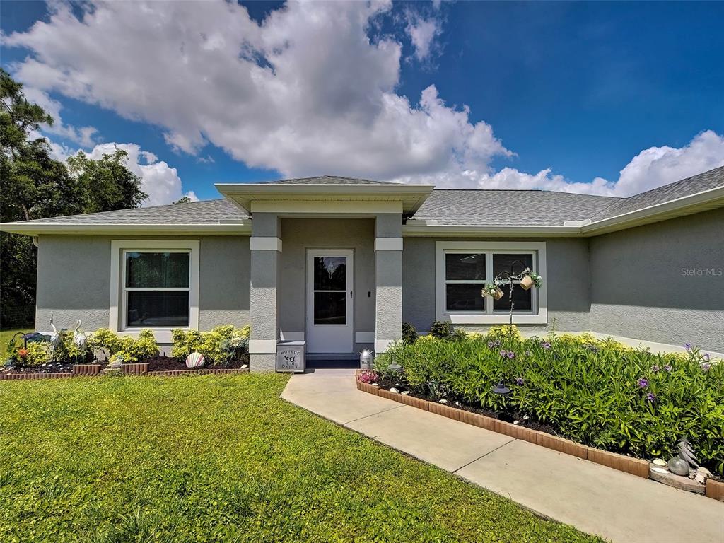 A single-story house with a gray exterior, a covered entryway, and a front walkway — 5236 BANNOCK CIRCLE, NORTH PORT, FL