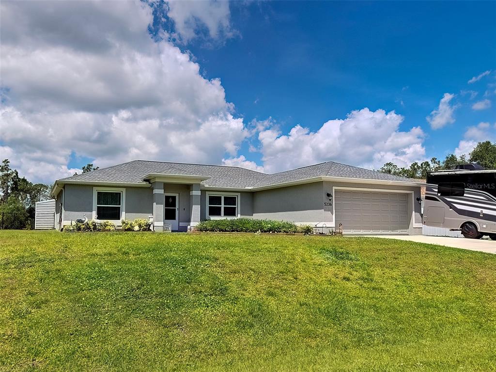 A single-story gray house with a two-car garage and a large front lawn — 5236 BANNOCK CIRCLE, NORTH PORT, FL