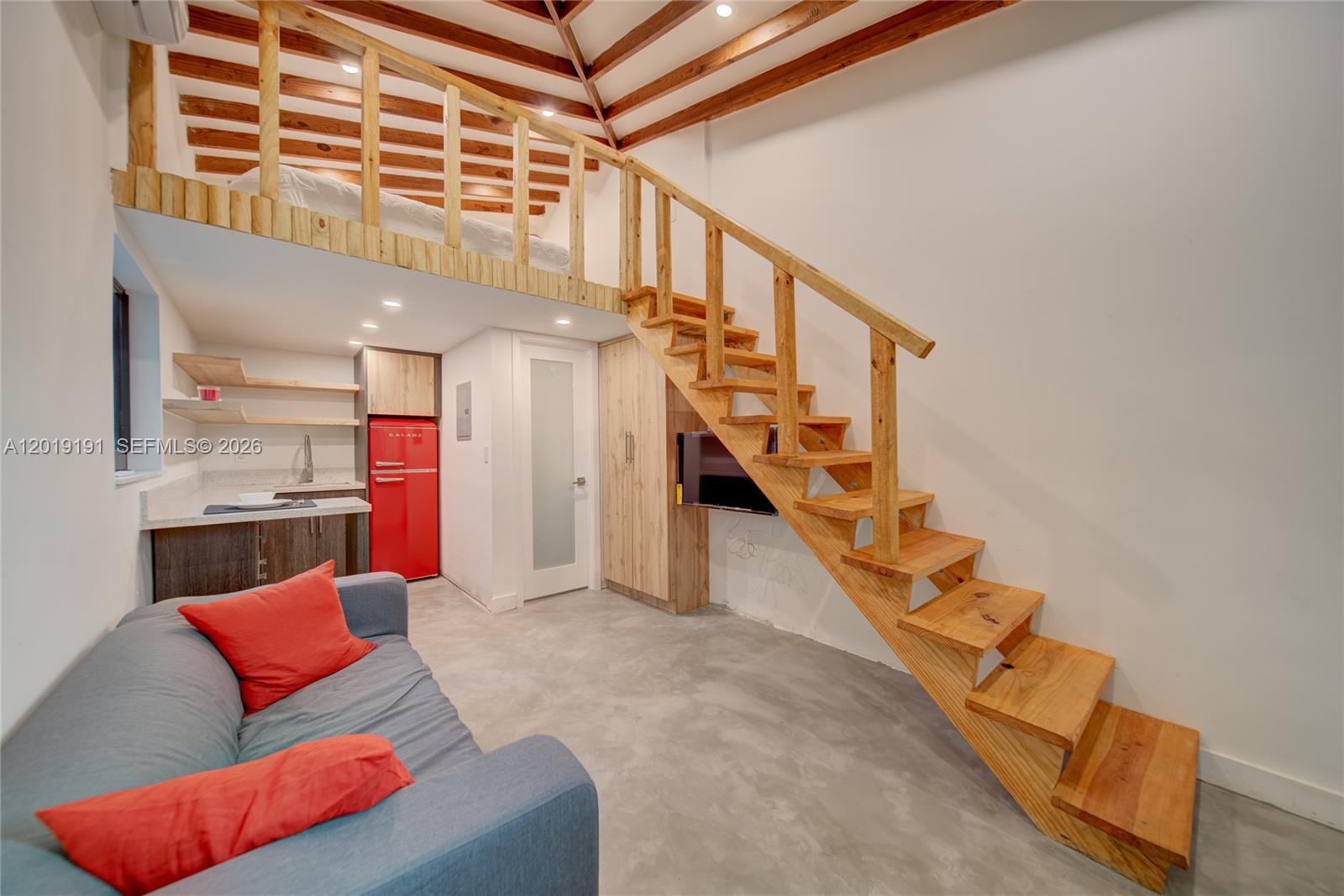 A small studio apartment features a lofted sleeping area, wooden staircase, and a red refrigerator — 6631 Tamiami Canal Rd, Miami FL 33126, MIAMI, FL