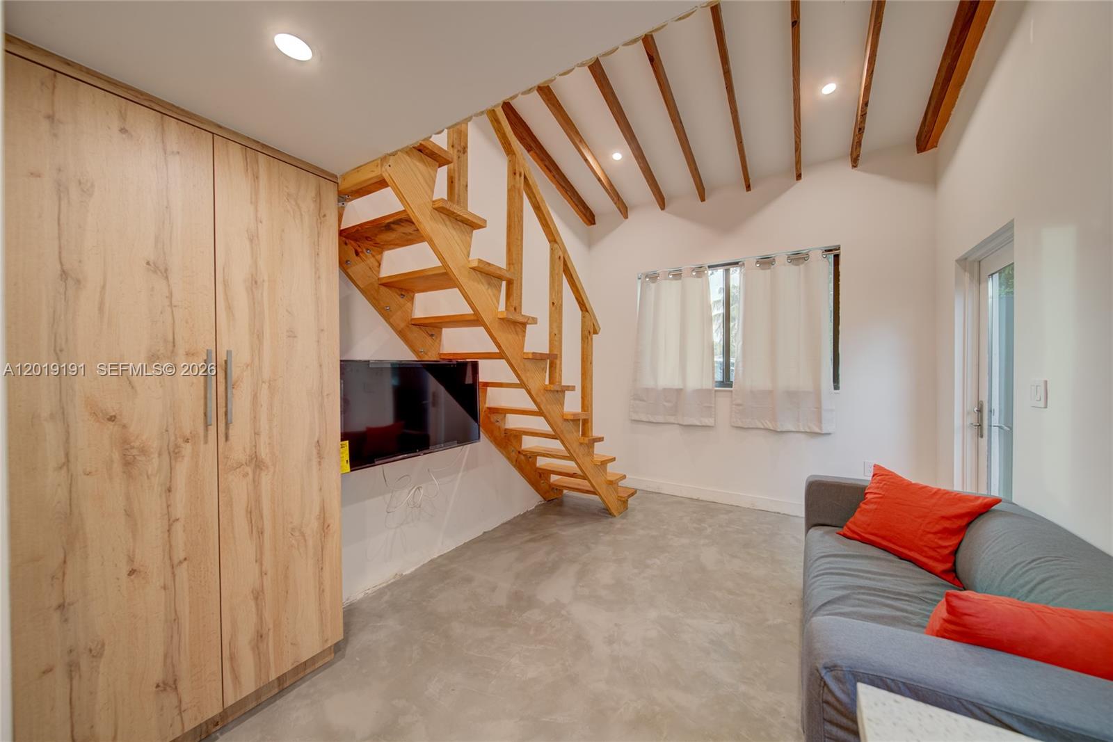 A living room features a wooden staircase, a grey sofa, and light wood cabinetry — 6631 Tamiami Canal Rd, Miami FL 33126, MIAMI, FL