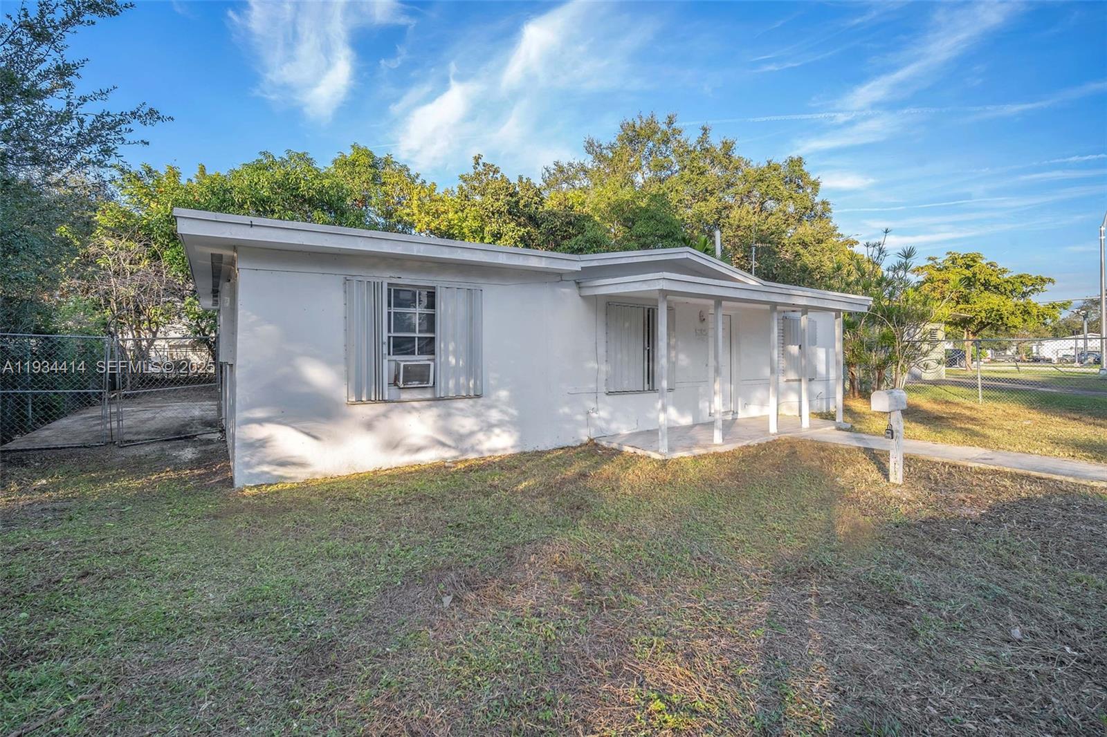 A single-story white house with a front porch and metal shutters stands on a lawn — 265 NW 135th, North Miami FL 33168, NORTH MIAMI, FL
