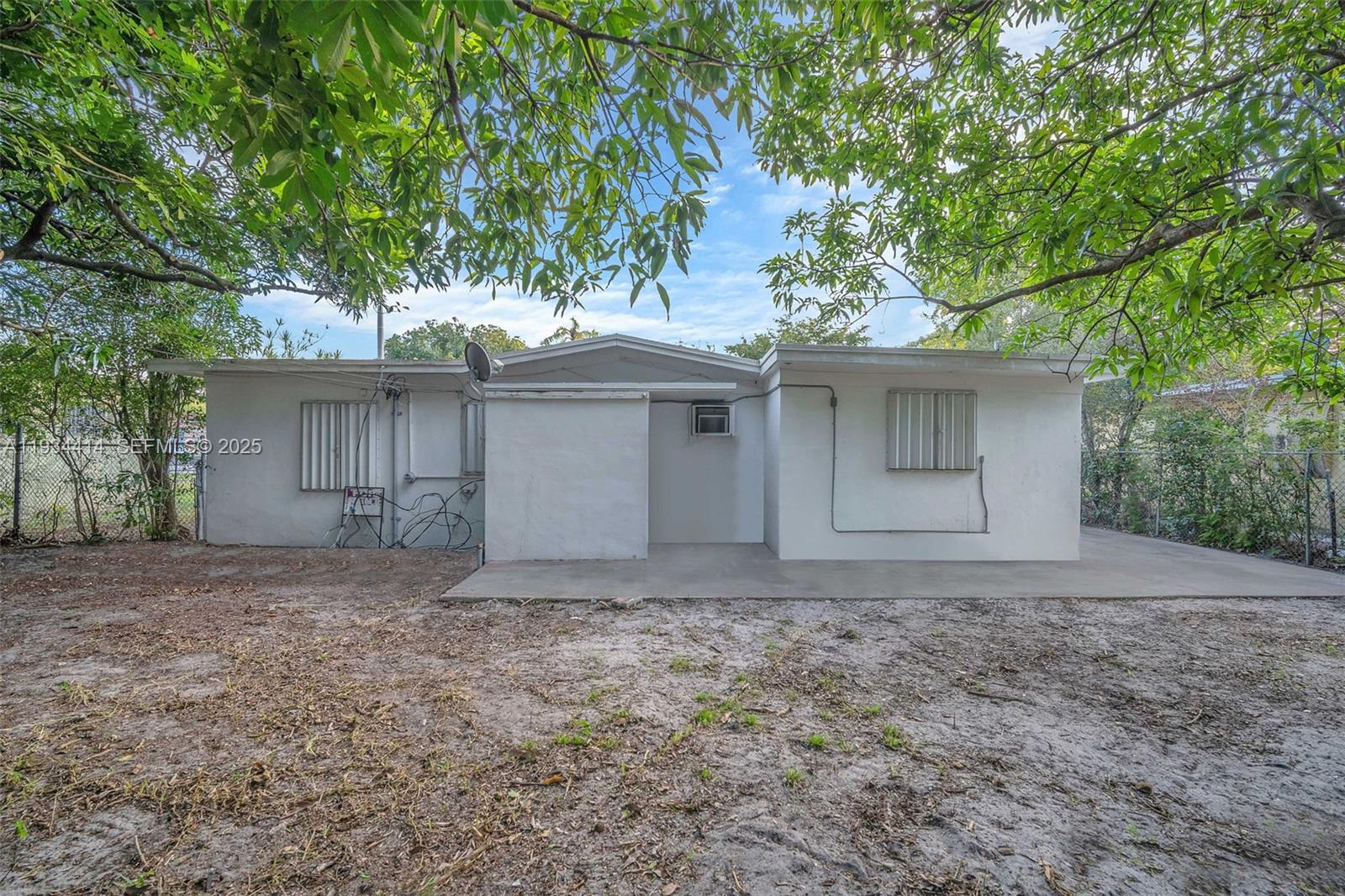 The exterior of a white, single-story house features a concrete patio and metal window shutters — 265 NW 135th, North Miami FL 33168, NORTH MIAMI, FL