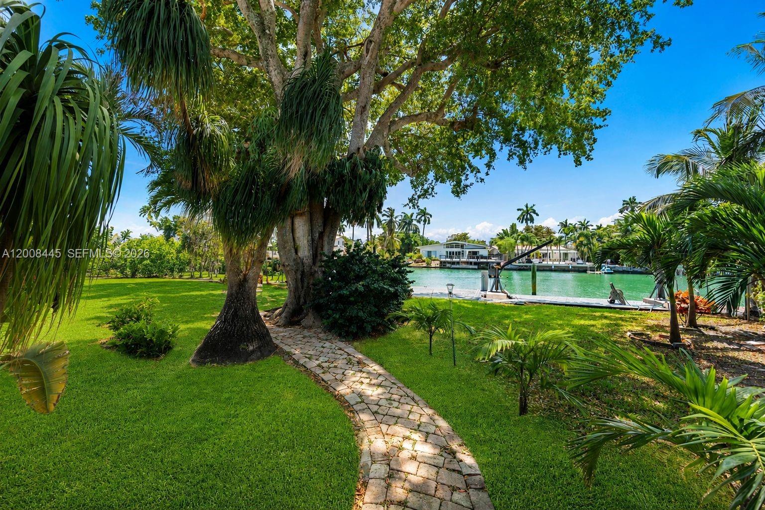 A stone path leads through a grassy yard toward a waterfront dock and canal — 540 S Shore Dr, Miami Beach FL 33141, MIAMI BEACH, FL