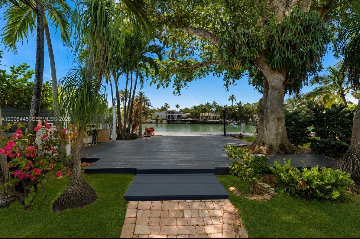 A dark wooden deck overlooks a canal surrounded by lush trees and tropical landscaping — 540 S Shore Dr, Miami Beach FL 33141, MIAMI BEACH, FL