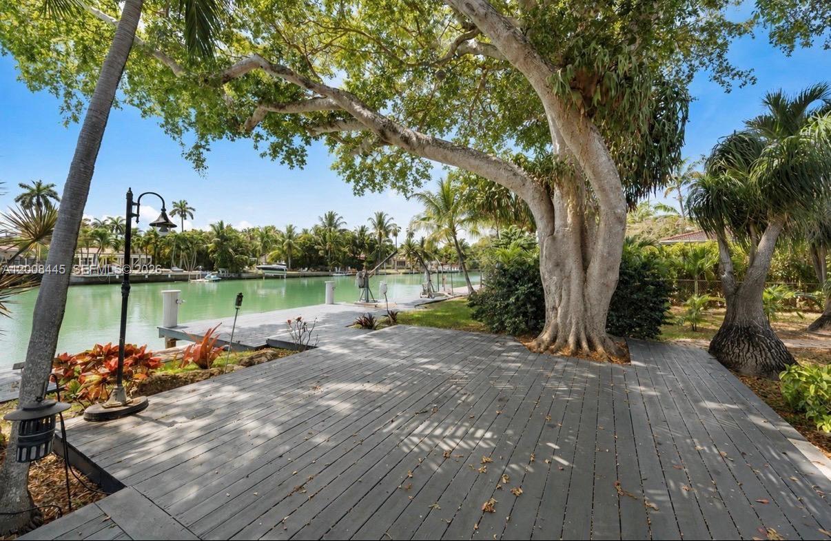 A wooden deck overlooks a canal with a large tree and a boat dock — 540 S Shore Dr, Miami Beach FL 33141, MIAMI BEACH, FL