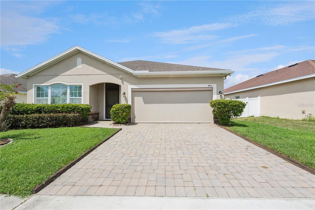 A single-story house with a beige stucco exterior, a paved driveway, and a two-car garage — 480 KESTREL DRIVE, GROVELAND, FL