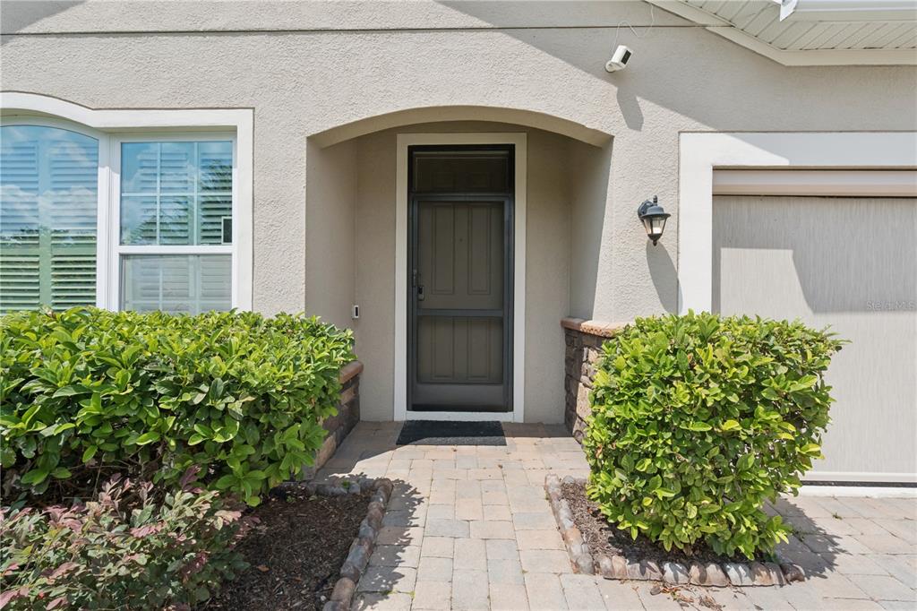 The exterior of a home features a front door with a screen, landscaping, and pavers — 480 KESTREL DRIVE, GROVELAND, FL