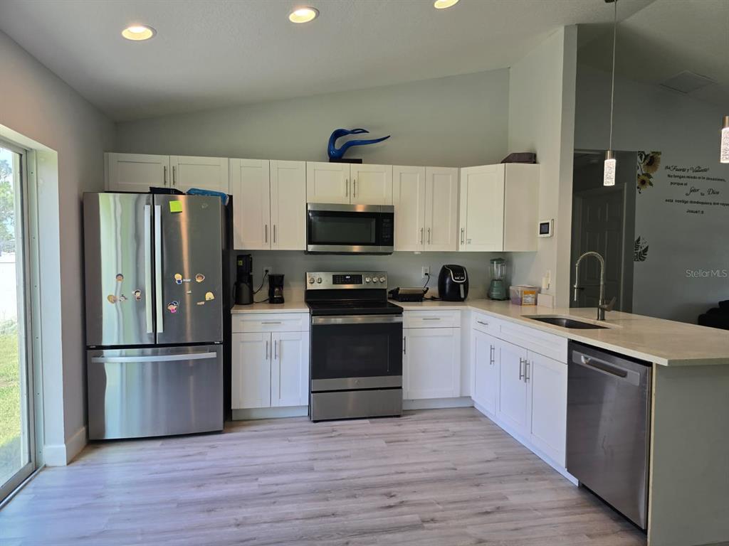 A kitchen with white cabinets, stainless steel appliances, and light wood-look flooring — 14512 SW 25TH LANE, OCALA, FL