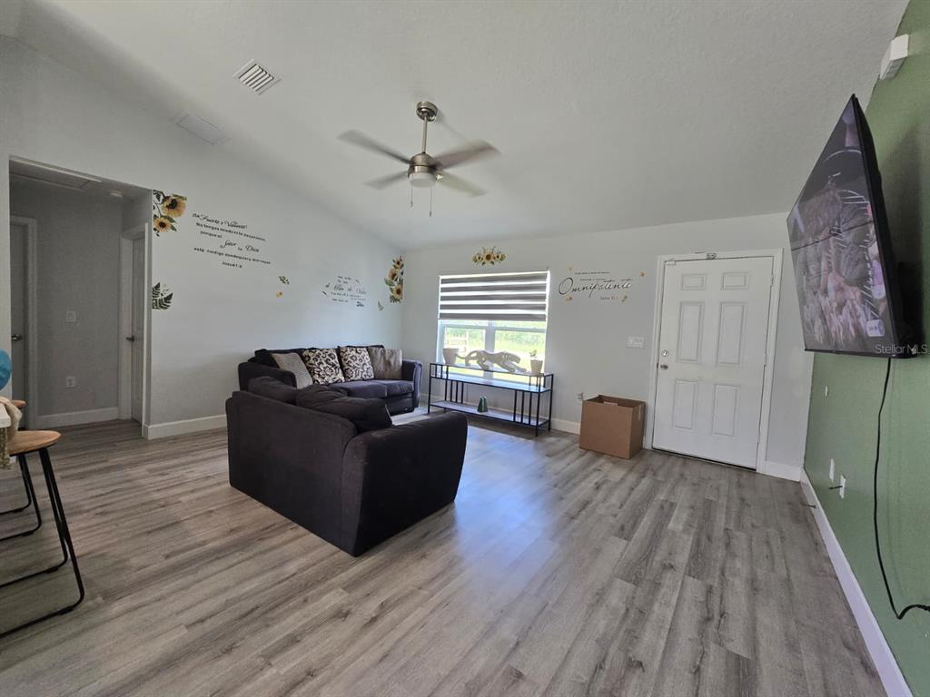 A living room features gray wood-look flooring, a dark sectional sofa, and a ceiling fan — 14512 SW 25TH LANE, OCALA, FL