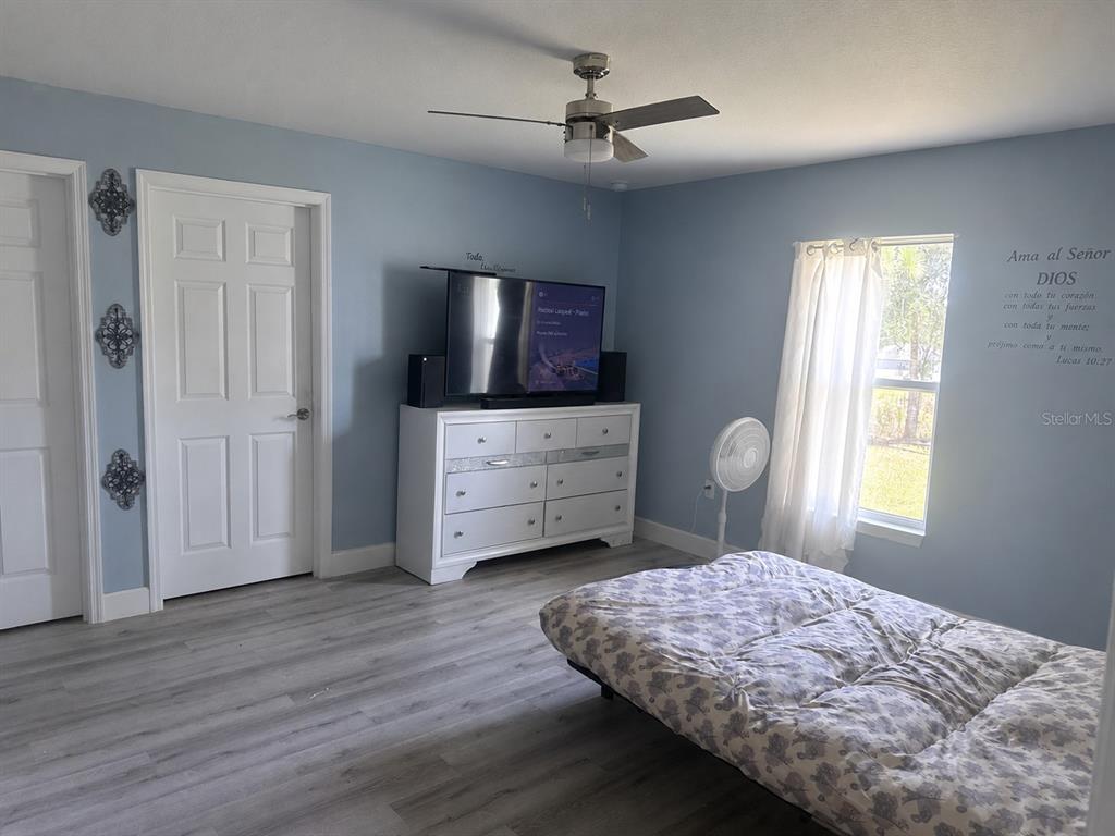 A bedroom with light blue walls, wood-look flooring, a white dresser, and a bed — 14512 SW 25TH LANE, OCALA, FL