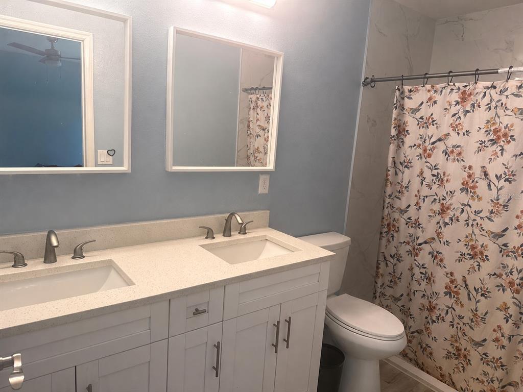 A bathroom features a double vanity with white cabinets, light countertops, and a floral shower curtain — 14512 SW 25TH LANE, OCALA, FL
