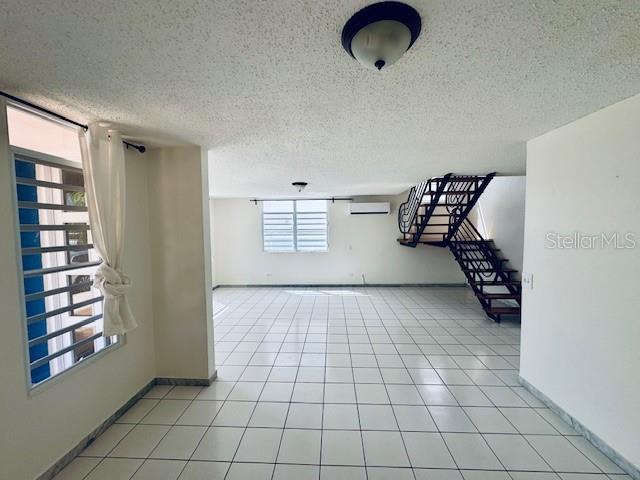 An empty room with white tiled floors, large windows, and a textured ceiling — 70 VIA PLAYERA, TOA BAJA, PR