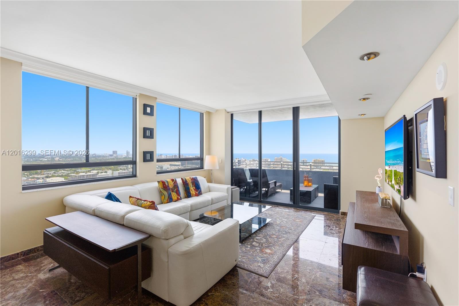 A living room with a white sectional sofa, marble floors, and floor-to-ceiling windows with views — 1330 West Ave, Miami Beach FL 33139, MIAMI BEACH, FL