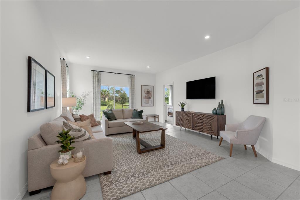 A living room features a beige sofa, a wooden coffee table, and a wall-mounted television — 4457 RIVER BEACON BOULEVARD, DAVENPORT, FL