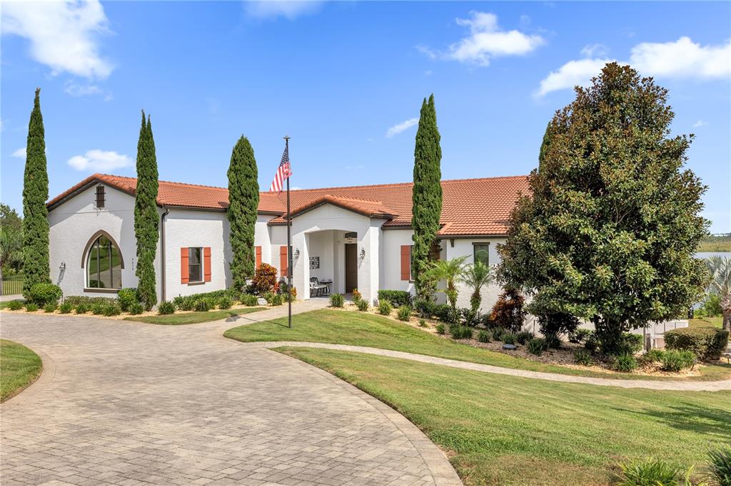 A single-story white stucco house with a red tile roof and a paved driveway — 7616 LILY COURT, GROVELAND, FL