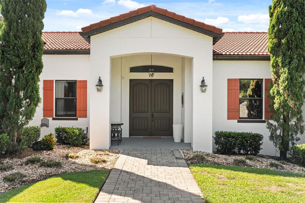 The exterior of a white house features a tiled roof, double front doors, and shutters — 7616 LILY COURT, GROVELAND, FL