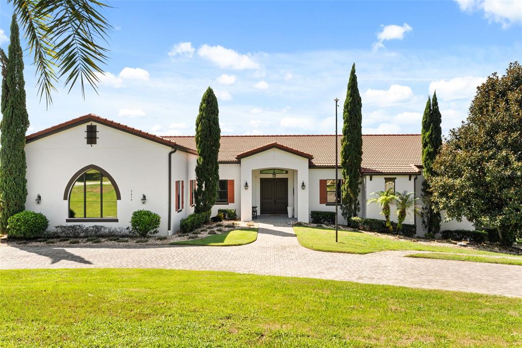 A single-story white stucco house with a tile roof and a paved driveway — 7616 LILY COURT, GROVELAND, FL