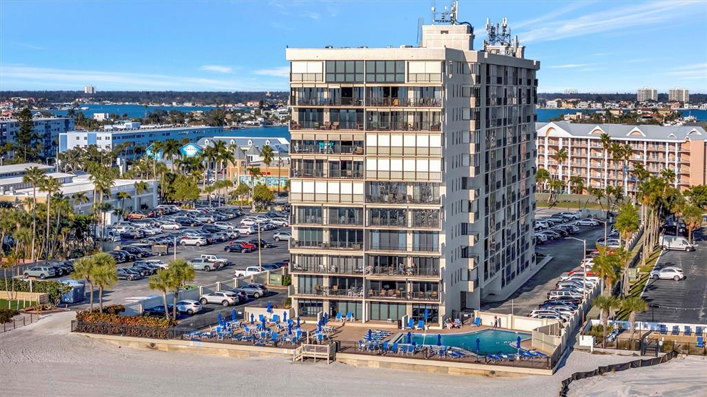 An aerial view of a multi-story beachfront condominium building with a pool and parking lot — 5396 GULF BOULEVARD UNIT 407, ST PETE BEACH, FL
