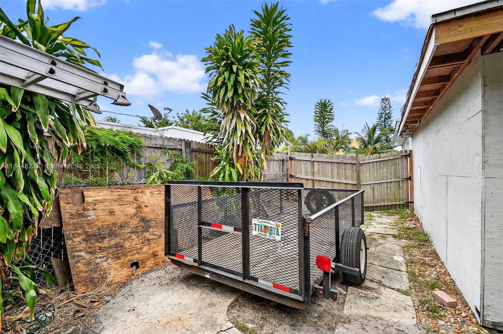A utility trailer sits on a concrete pad next to a house and wooden fence — 435 Avenida Alegre, West Palm Beach FL 33405, WEST PALM BEACH, FL