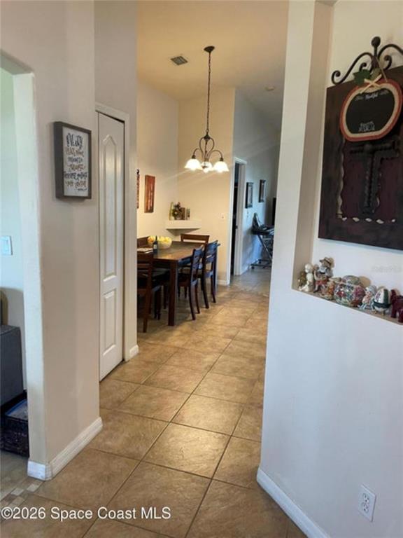 A tiled hallway leads to a dining area with a hanging light fixture and table — 616 PEACHTREE STREET, TITUSVILLE, FL
