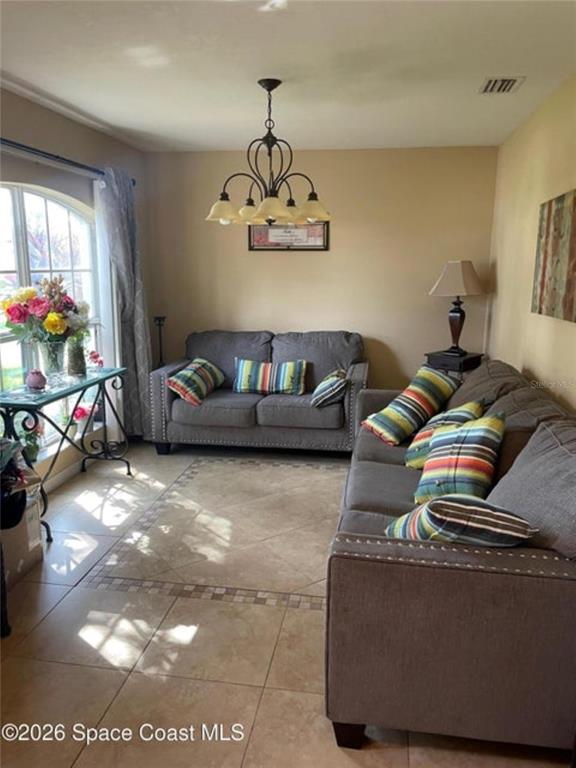 A living room features two gray sofas, a chandelier, and tile flooring — 616 PEACHTREE STREET, TITUSVILLE, FL