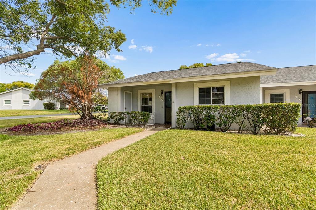 A single-story gray house with a walkway, lawn, and landscaping under a blue sky — 7725 DANUBE DRIVE UNIT 0000, HUDSON, FL