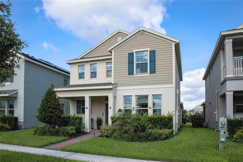 A two-story house with tan siding, a front porch, and a landscaped front yard — 16625 POINT ROCK DRIVE, WINTER GARDEN, FL