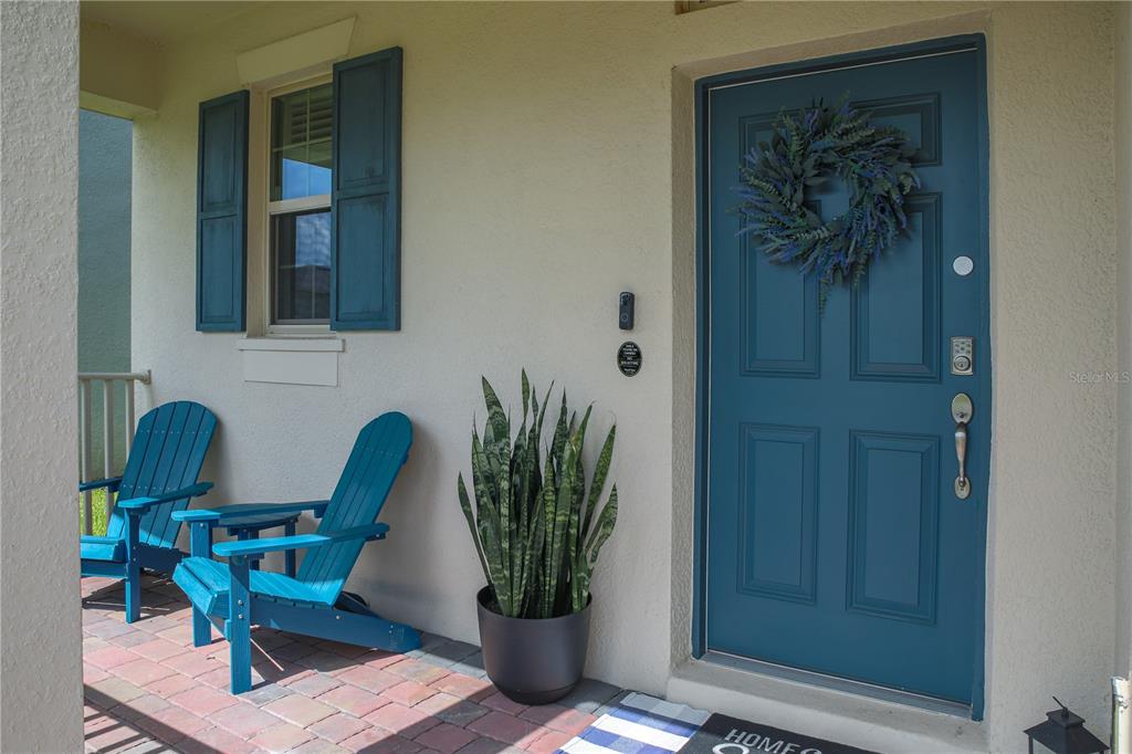 A front porch features two blue Adirondack chairs, a potted snake plant, and a blue door — 16625 POINT ROCK DRIVE, WINTER GARDEN, FL