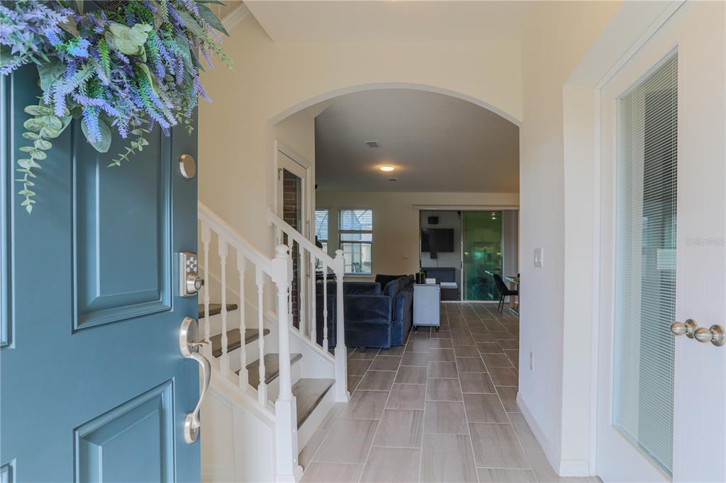 An entryway with tile flooring leads to a living area through an arched opening — 16625 POINT ROCK DRIVE, WINTER GARDEN, FL