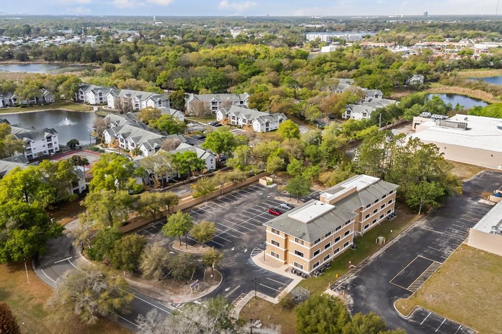 An aerial view shows a multi-story office building with a parking lot near apartment complexes — 1490 SUNSHADOW DRIVE, CASSELBERRY, FL