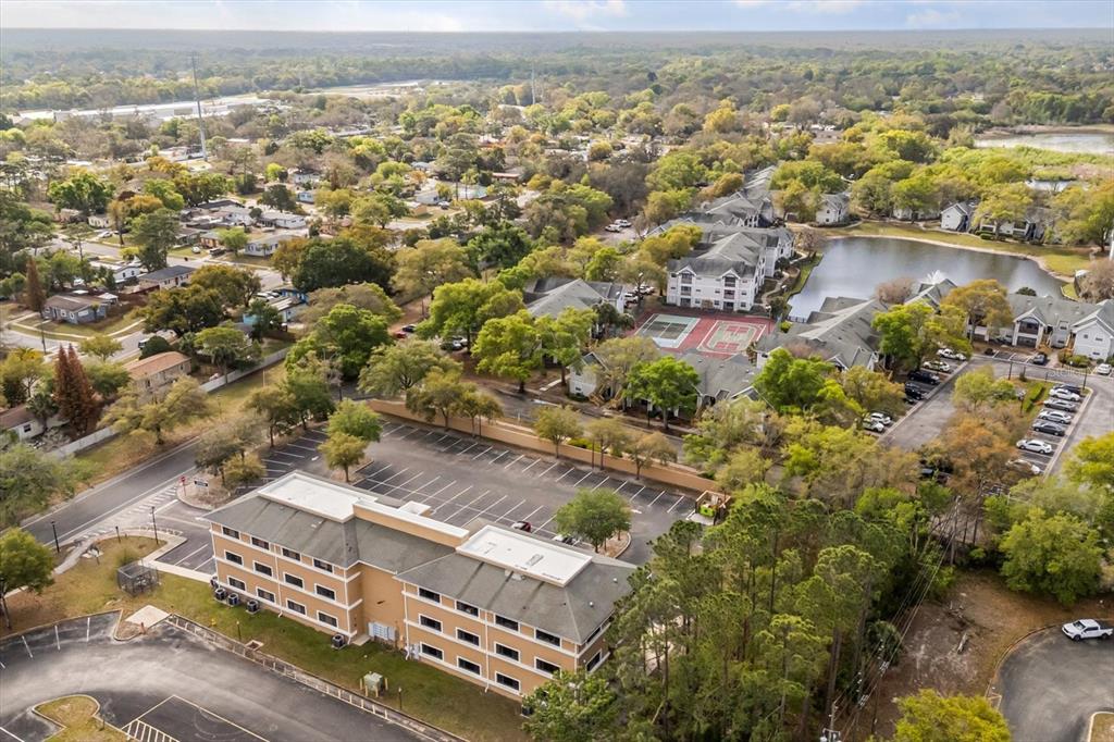 An aerial view shows a multi-story hotel building with a parking lot and nearby apartments — 1490 SUNSHADOW DRIVE, CASSELBERRY, FL