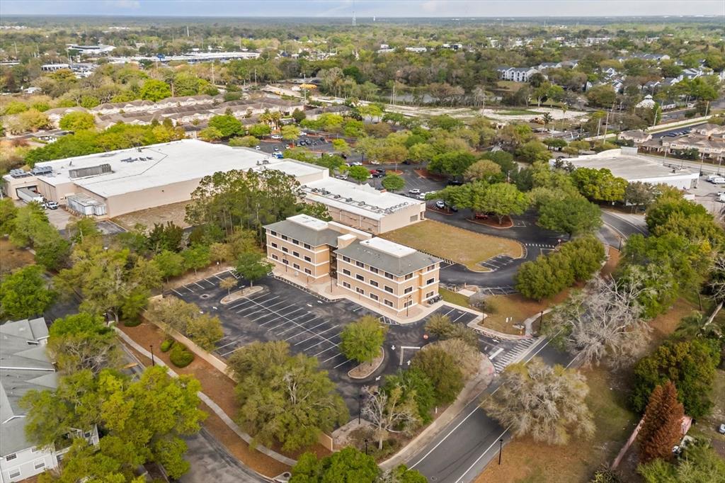 An aerial view shows a multi-story office building surrounded by parking lots and green trees — 1490 SUNSHADOW DRIVE, CASSELBERRY, FL