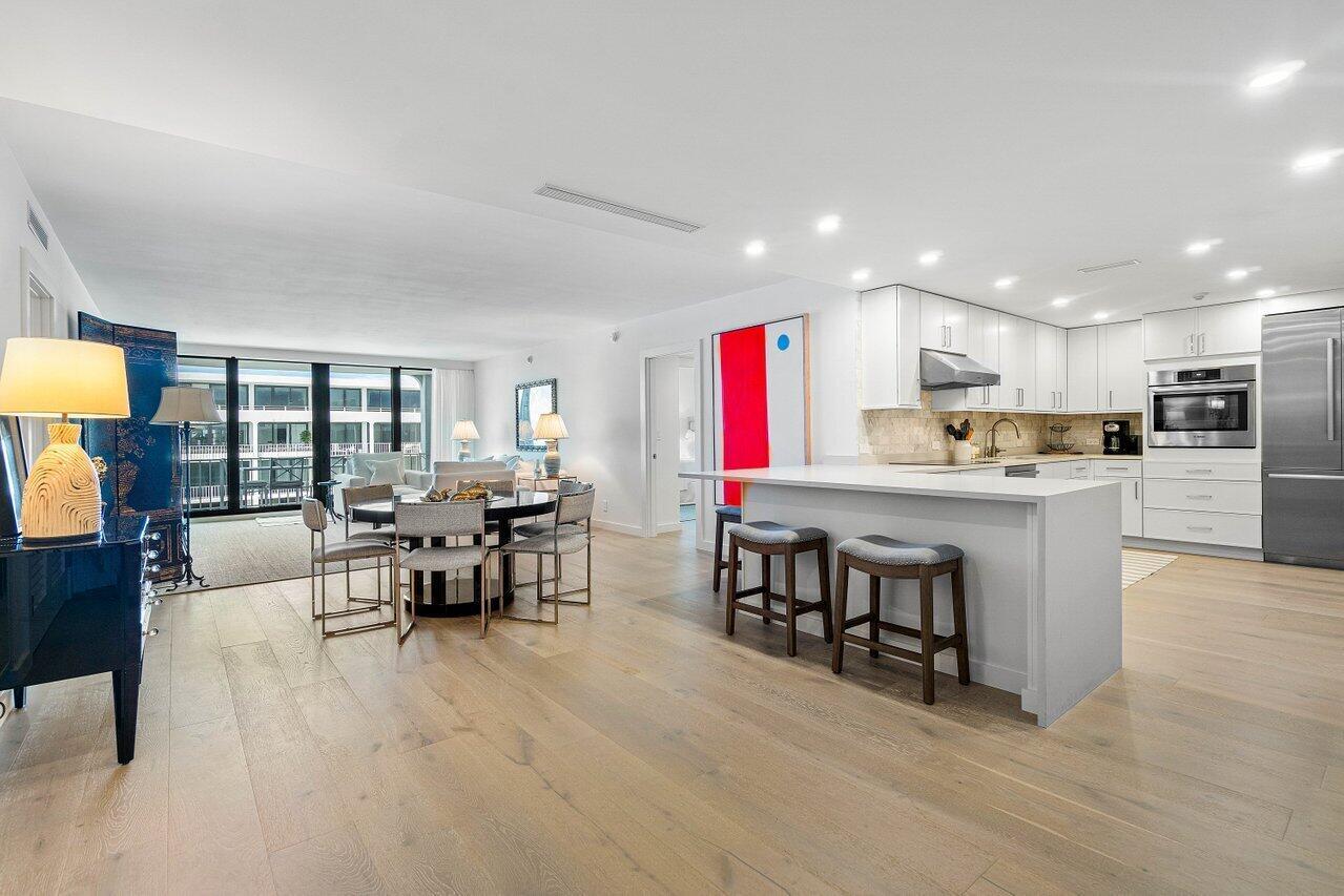 An open-concept kitchen and dining area features light wood floors, white cabinetry, and a balcony — 2784 S Ocean Boulevard # 403s, Palm Beach FL 33480, PALM BEACH, FL