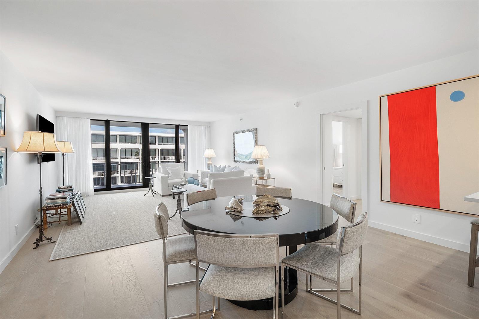 A dining area with a round black table sits before a bright, open-concept living room — 2784 S Ocean Boulevard # 403s, Palm Beach FL 33480, PALM BEACH, FL