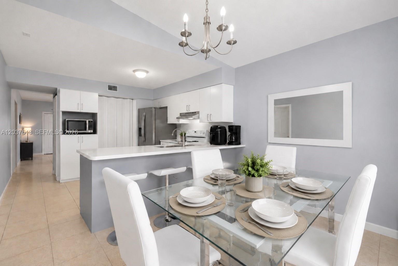 A dining area with a glass table and white chairs sits adjacent to a modern kitchen — 2886 W 74th Pl, Hialeah FL 33018, HIALEAH, FL