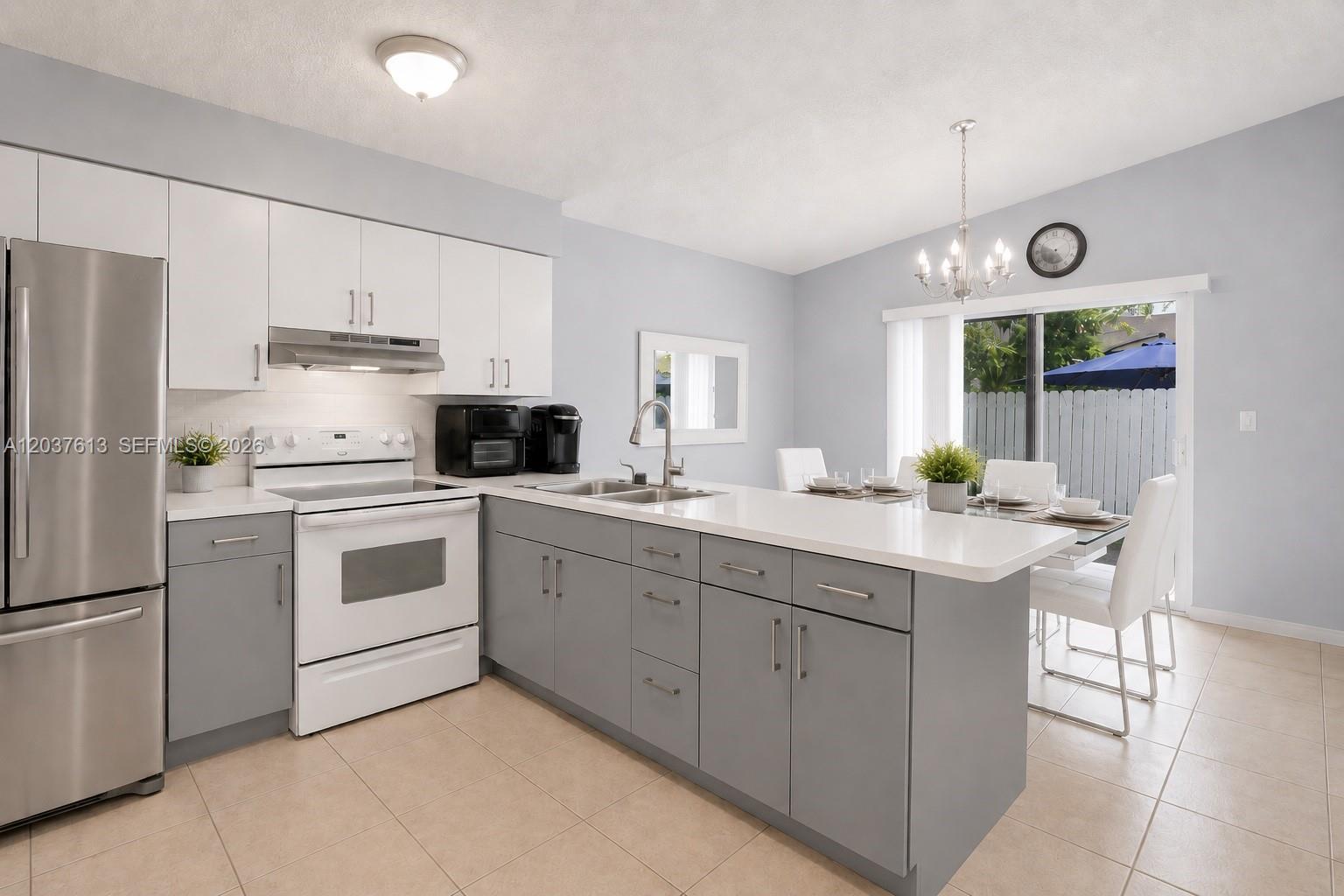 A kitchen features gray lower cabinets, white upper cabinets, stainless steel appliances, and a dining area — 2886 W 74th Pl, Hialeah FL 33018, HIALEAH, FL