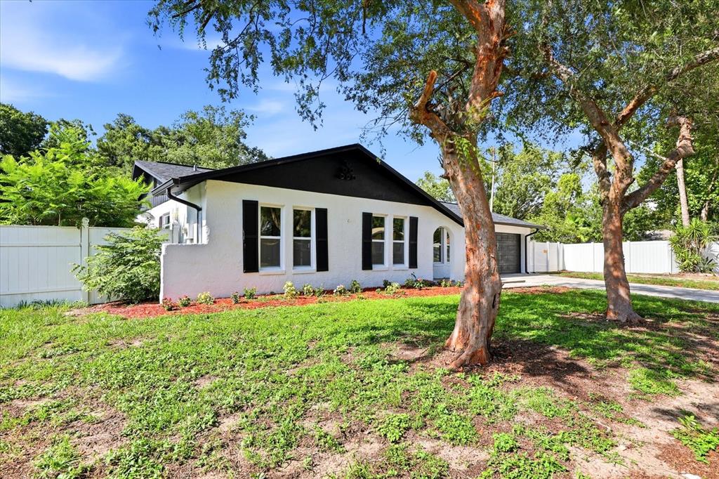 A white single-story house with black trim and shutters sits behind a grassy front yard — 3304 KING RICHARD COURT, SEFFNER, FL