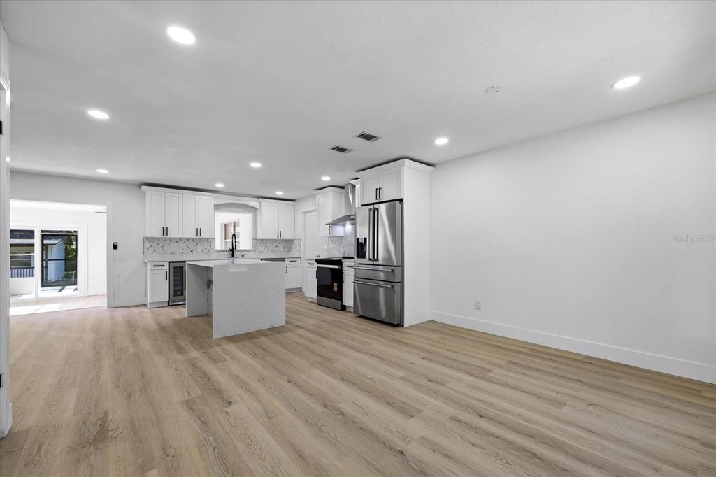A modern kitchen features white cabinetry, a central island, and stainless steel appliances — 3304 KING RICHARD COURT, SEFFNER, FL