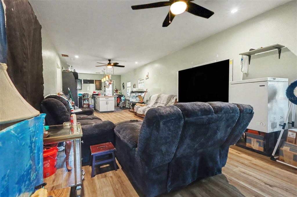 A living room with dark furniture, a large television, and an open kitchen in back — 1054 STATE ROAD 60 E, LAKE WALES, FL