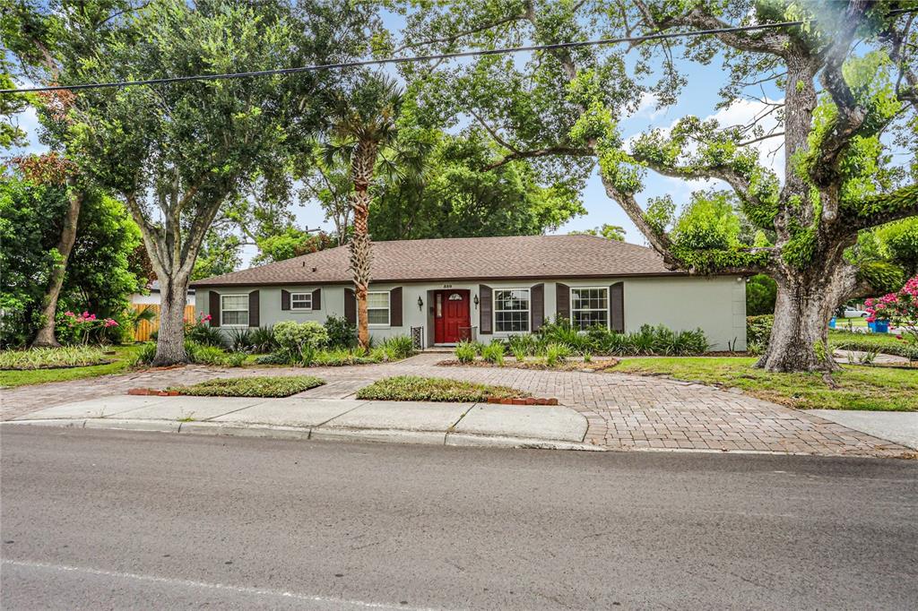 A single-story house with a red front door, brown shutters, and a brick driveway — 550 ARAPAHO TRAIL, MAITLAND, FL