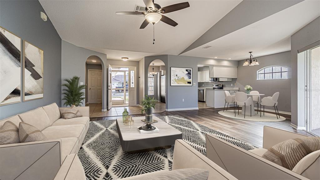 A living room with a geometric rug, light-colored sofa, and an open-concept dining area — 11048 MOSHIE LANE, SAN ANTONIO, FL