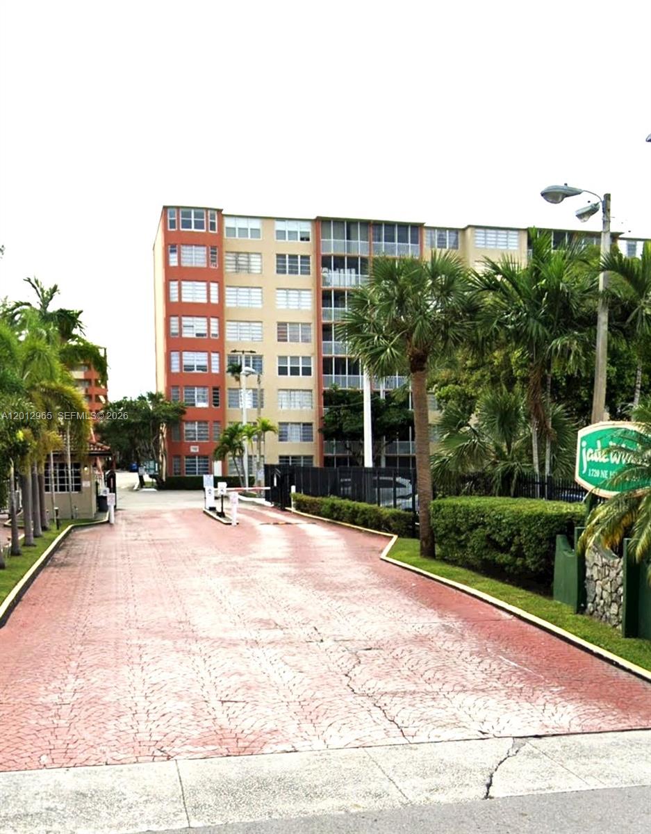 A paved driveway leads to the gated entrance of a multi-story apartment building — 1770 NE 191st St # 1, Miami FL 33179, MIAMI, FL
