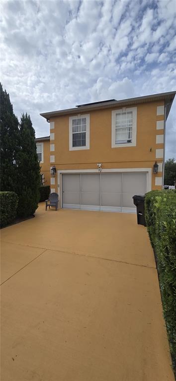 A two-story house with a yellow stucco exterior, white trim, and a three-car garage — 116 FLATFISH COURT, KISSIMMEE, FL