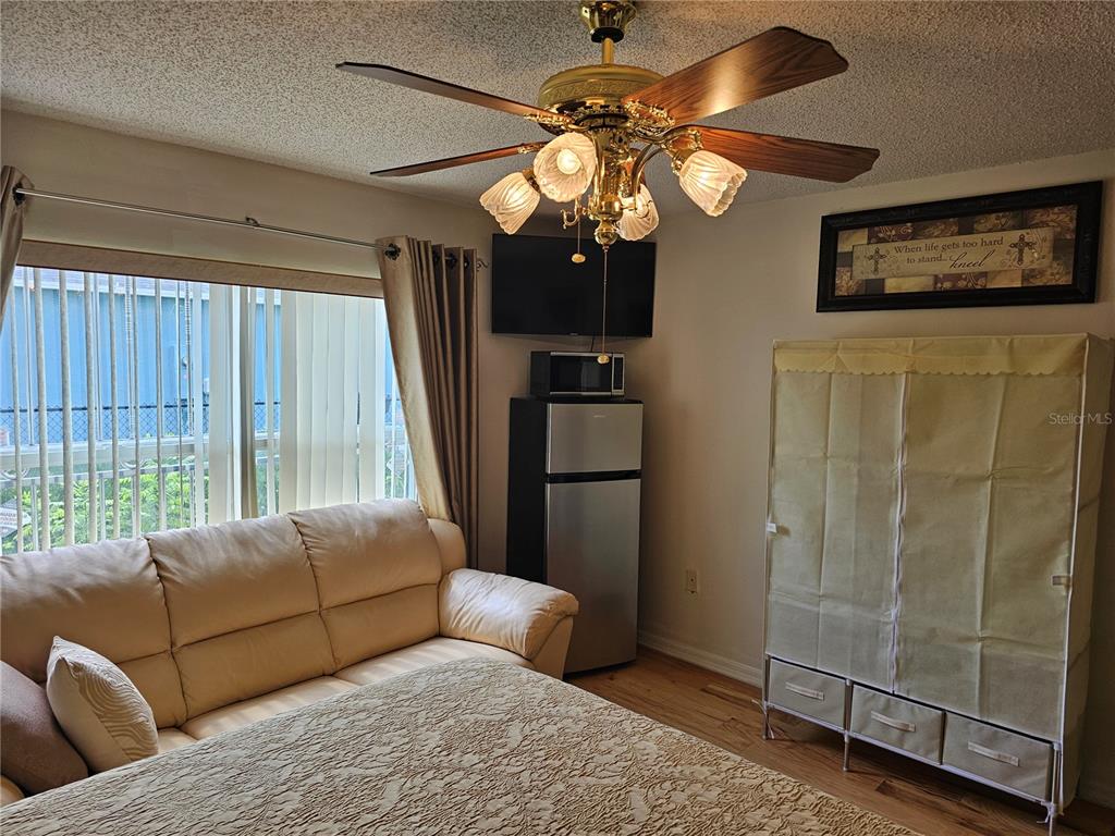 A bedroom features a ceiling fan, a sofa, a small refrigerator, and a portable wardrobe — 116 FLATFISH COURT, KISSIMMEE, FL